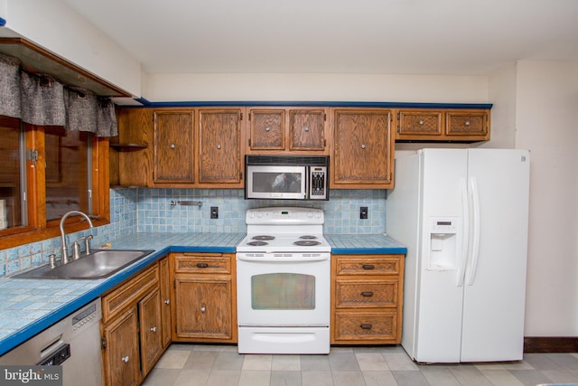 kitchen featuring tile countertops, white appliances, sink, and tasteful backsplash