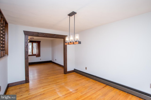 unfurnished dining area featuring baseboard heating, light hardwood / wood-style flooring, and a notable chandelier