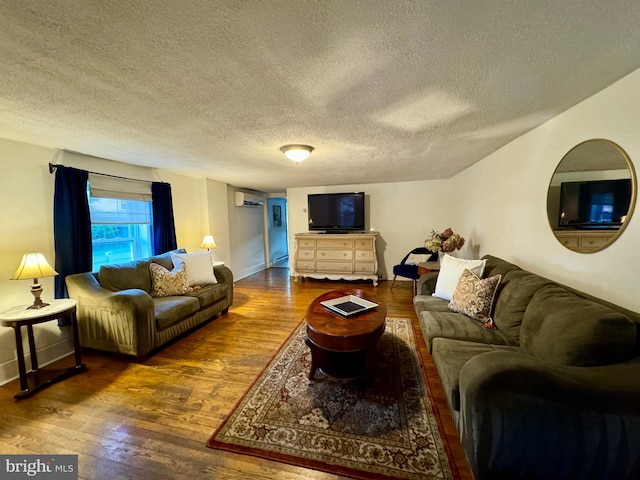 living room featuring a wall mounted AC, dark hardwood / wood-style floors, and a textured ceiling