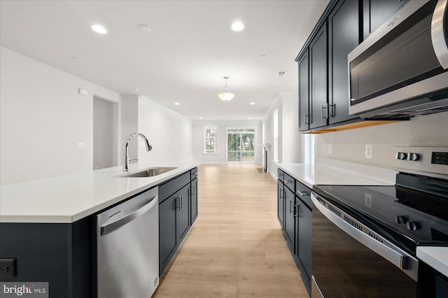 kitchen with pendant lighting, sink, an island with sink, light hardwood / wood-style floors, and stainless steel appliances