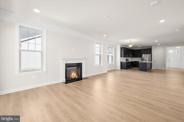 unfurnished living room with ornamental molding and light wood-type flooring