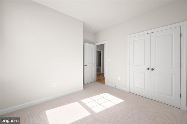 unfurnished bedroom with light carpet and a closet