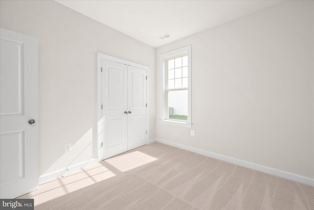 unfurnished bedroom featuring light carpet and a closet