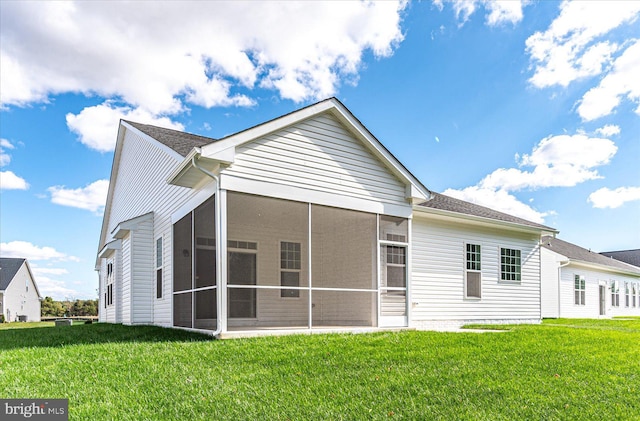 rear view of property with a lawn and a sunroom