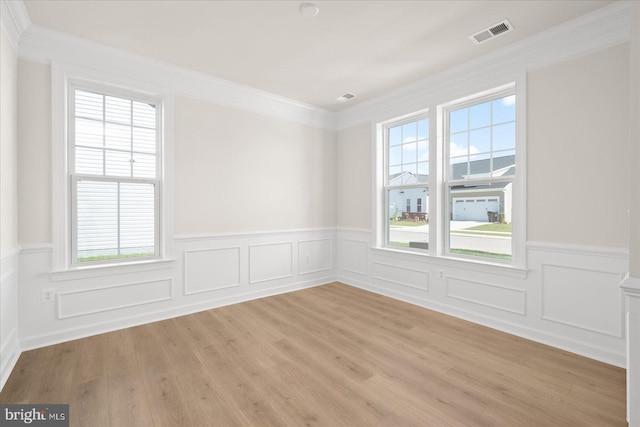 empty room with crown molding and light hardwood / wood-style flooring