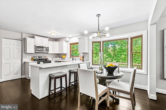 kitchen featuring pendant lighting, white cabinets, appliances with stainless steel finishes, a notable chandelier, and a kitchen island