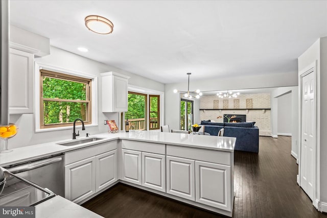 kitchen featuring kitchen peninsula, sink, decorative light fixtures, an inviting chandelier, and white cabinets