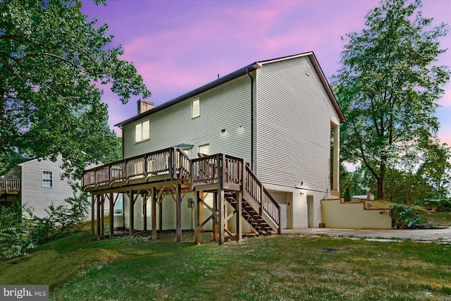 back house at dusk with a lawn, a garage, and a deck