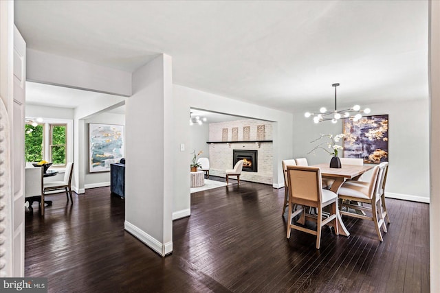 dining room with dark hardwood / wood-style flooring, a fireplace, and an inviting chandelier