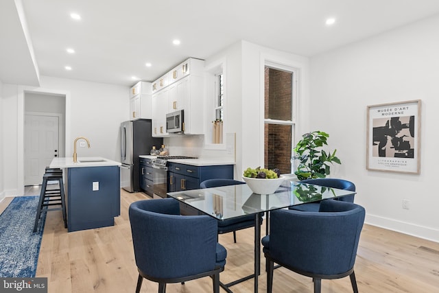 dining space with sink and light hardwood / wood-style flooring