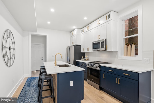 kitchen featuring appliances with stainless steel finishes, tasteful backsplash, sink, white cabinetry, and an island with sink