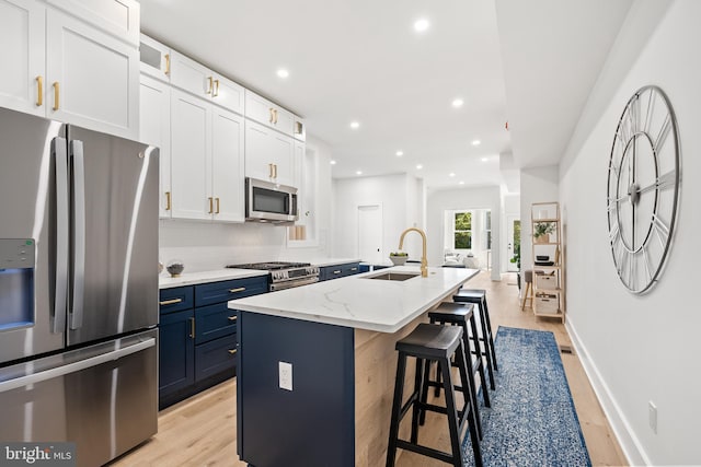 kitchen featuring appliances with stainless steel finishes, sink, a center island with sink, white cabinetry, and a breakfast bar area