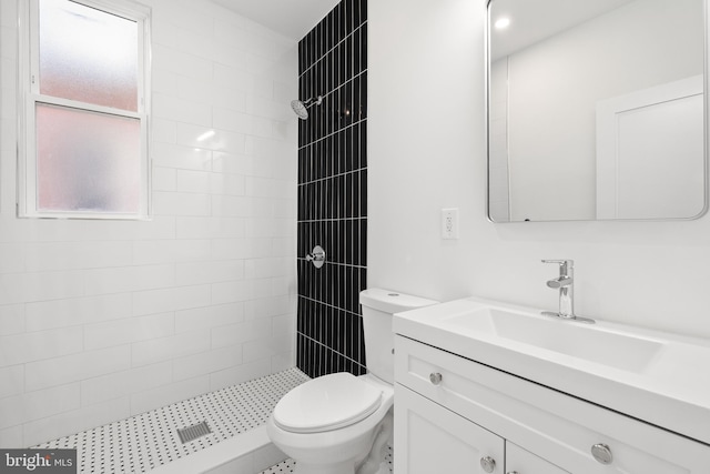 bathroom featuring tiled shower, vanity, and toilet