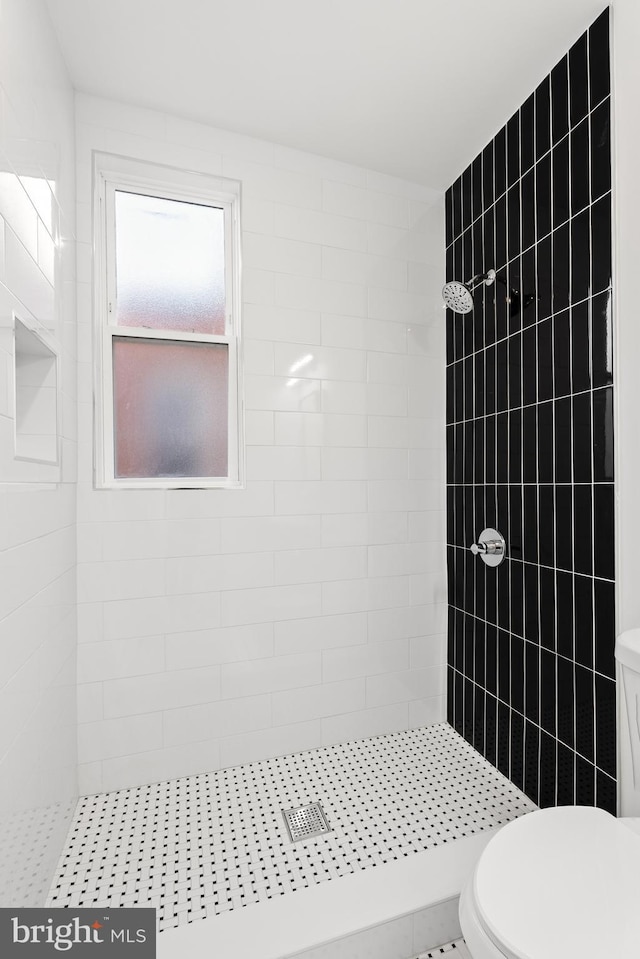 bathroom featuring tile patterned floors, toilet, and tiled shower