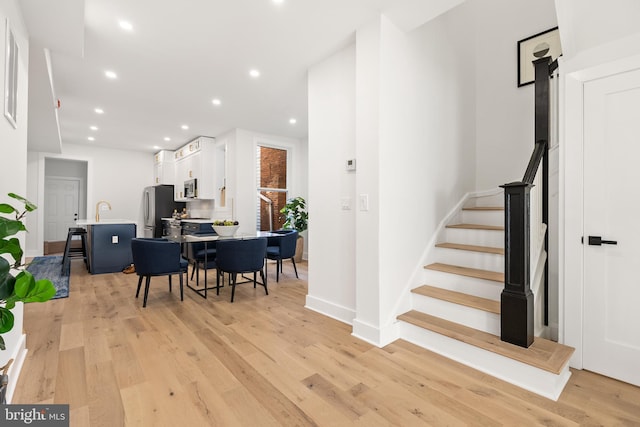 stairs with hardwood / wood-style floors and sink