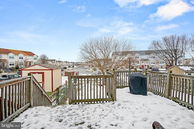 snow covered deck with a grill and a storage shed