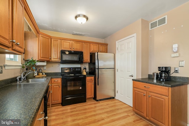 kitchen with light wood-type flooring, sink, and black appliances