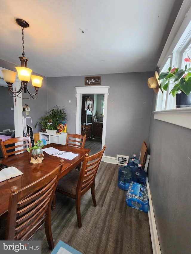 dining space featuring dark hardwood / wood-style flooring and a chandelier