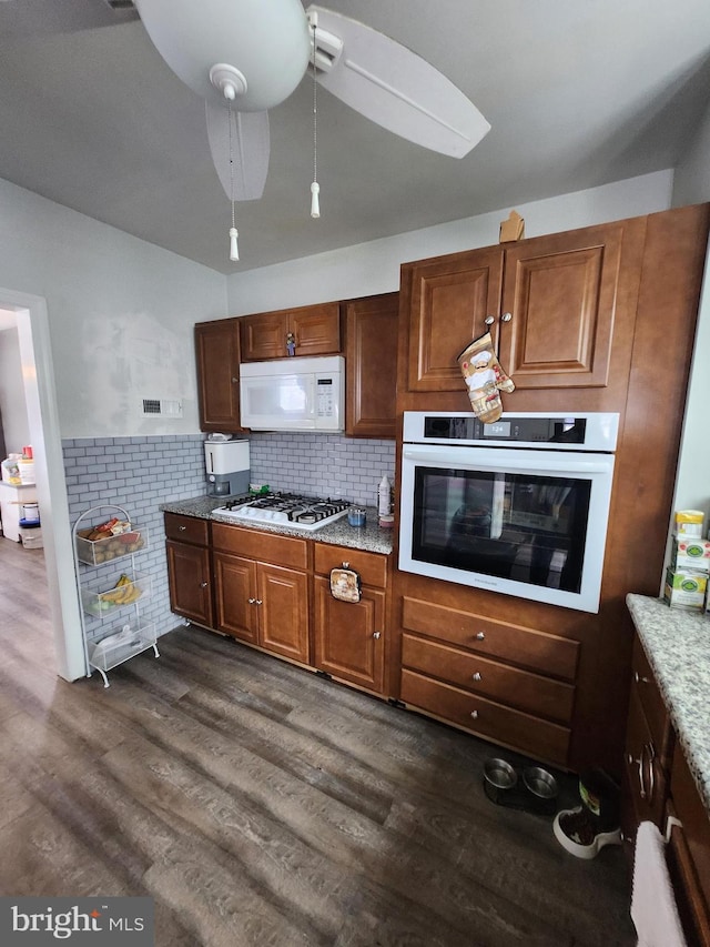 kitchen with backsplash, ceiling fan, white appliances, and dark wood-type flooring