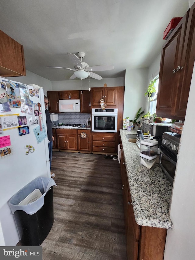 kitchen with decorative backsplash, light stone countertops, stainless steel appliances, sink, and dark hardwood / wood-style floors