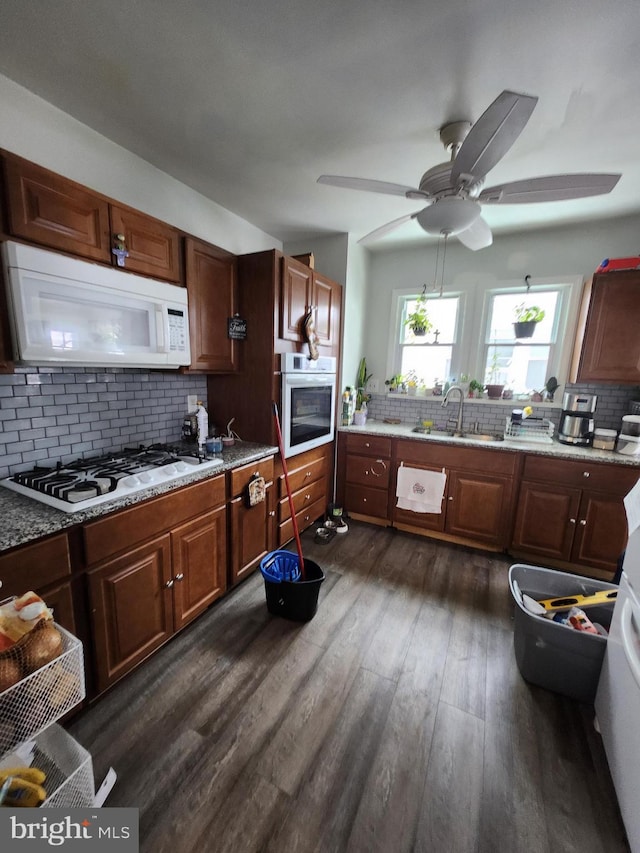 kitchen with dark hardwood / wood-style flooring, white appliances, sink, and tasteful backsplash