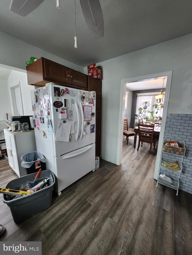 kitchen with dark brown cabinets, white refrigerator, and dark wood-type flooring