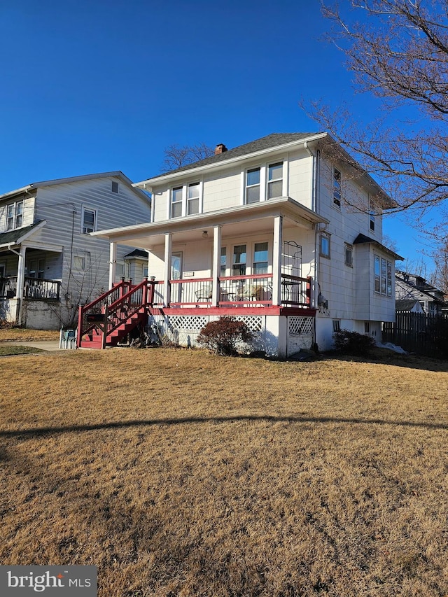 rear view of house with covered porch and a yard