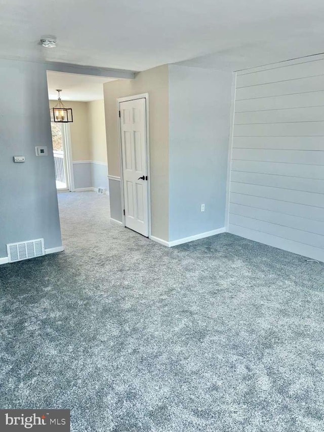 carpeted spare room featuring an inviting chandelier