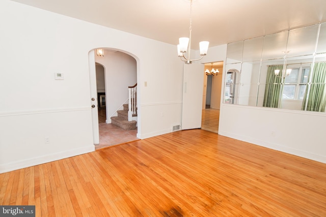 unfurnished room with hardwood / wood-style floors and an inviting chandelier