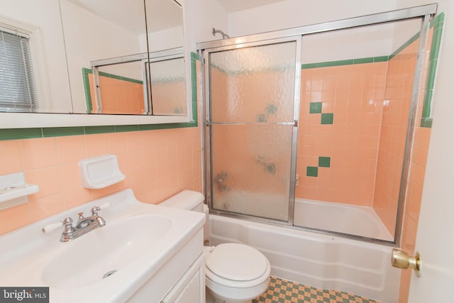 full bathroom with tasteful backsplash, vanity, shower / bath combination with glass door, tile walls, and toilet