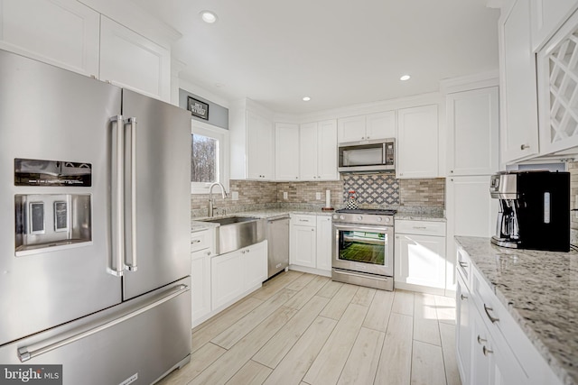 kitchen featuring sink, stainless steel appliances, light stone counters, and white cabinets