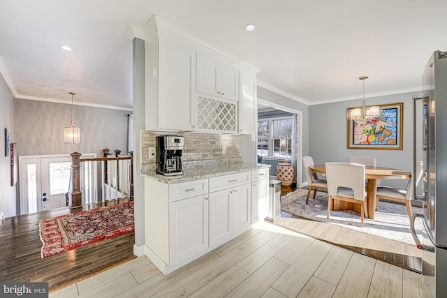 kitchen with crown molding, hanging light fixtures, white cabinets, light stone countertops, and a notable chandelier