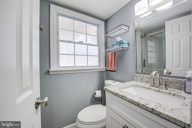 bathroom featuring toilet, a shower with shower door, and vanity