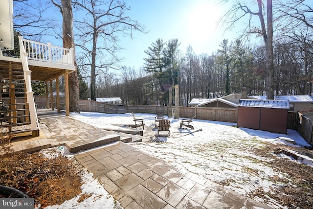 snow covered patio featuring a wooden deck and a hot tub