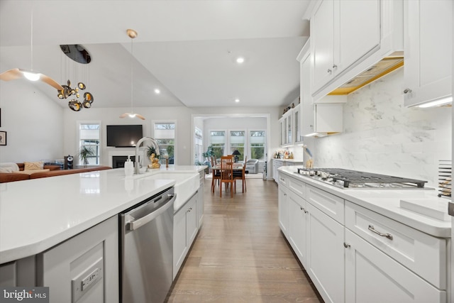 kitchen with white cabinets, decorative light fixtures, backsplash, and stainless steel appliances