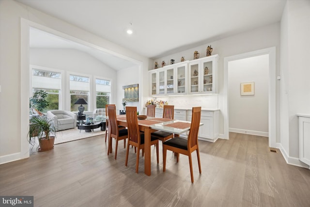 dining area with light hardwood / wood-style floors and vaulted ceiling