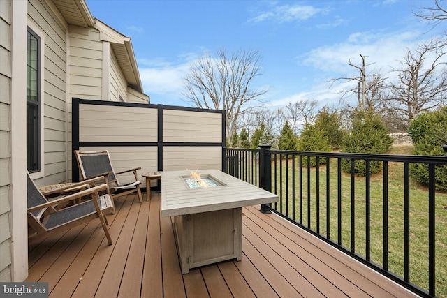 wooden terrace featuring a yard and a fire pit