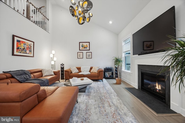 living room featuring light wood-type flooring, high vaulted ceiling, and an inviting chandelier