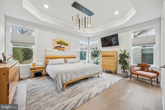 bedroom with hardwood / wood-style floors, a tray ceiling, and ornamental molding