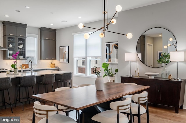 dining area with a chandelier, sink, and light hardwood / wood-style floors