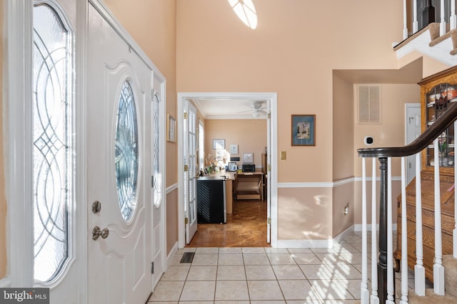 tiled entryway with ceiling fan and ornamental molding