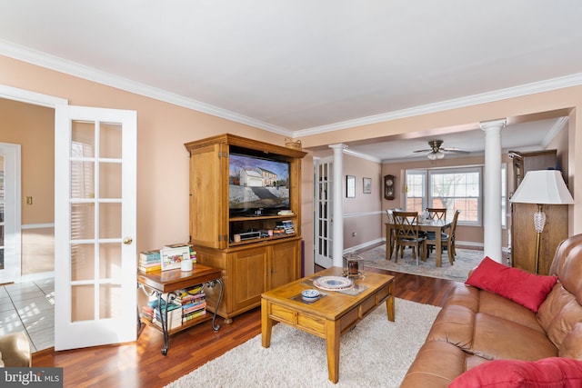 living room featuring dark wood-type flooring, ornate columns, ornamental molding, and ceiling fan