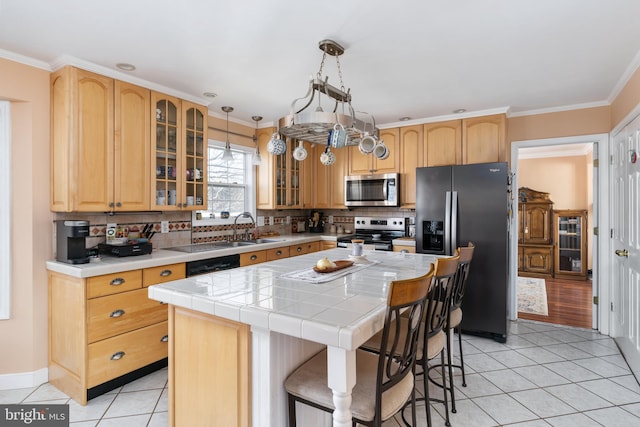 kitchen featuring decorative light fixtures, tile countertops, a center island, light tile patterned flooring, and appliances with stainless steel finishes