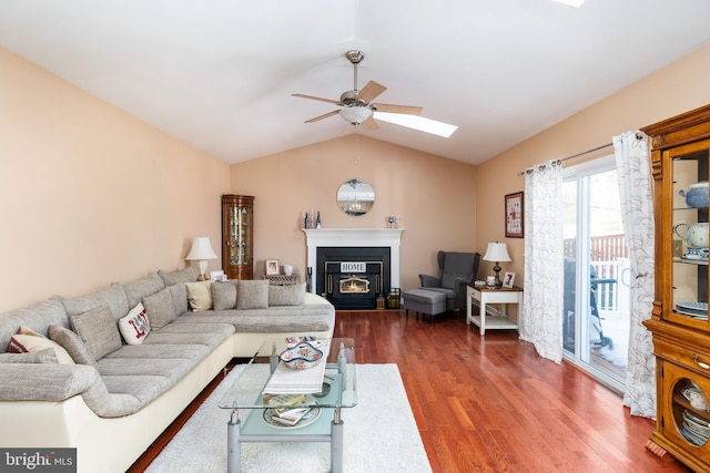 living room featuring ceiling fan, dark hardwood / wood-style flooring, and lofted ceiling with skylight