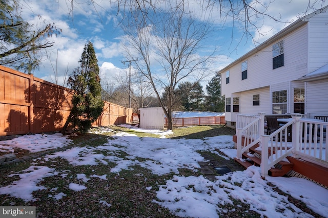 snowy yard featuring a wooden deck and a shed