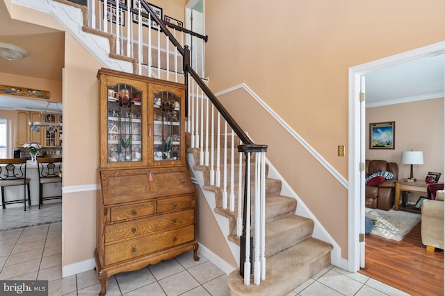 stairs featuring crown molding and tile patterned floors