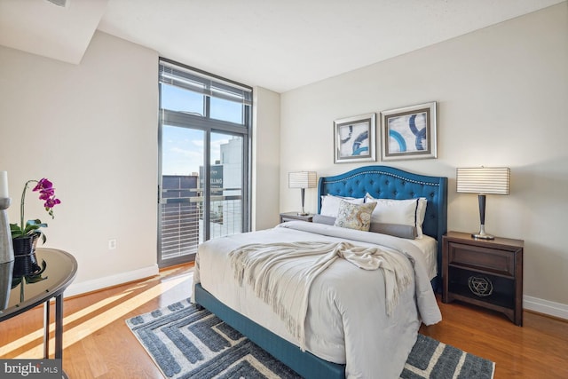 bedroom featuring hardwood / wood-style flooring, expansive windows, and access to outside