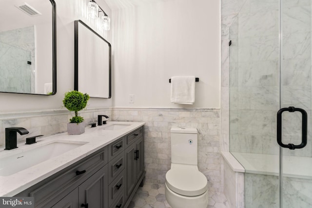 bathroom featuring vanity, a shower with door, toilet, and tile walls