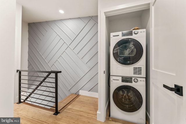 washroom with stacked washer / drying machine and wood-type flooring