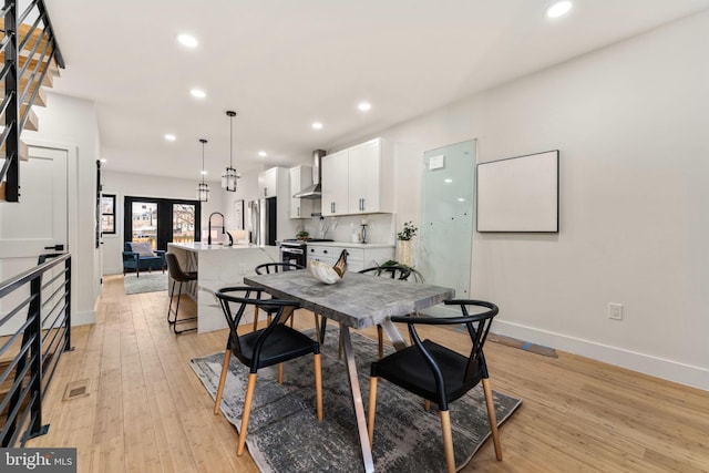 dining space with french doors, light hardwood / wood-style floors, and sink